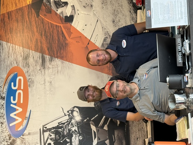 A shop owner at his desk with two of his team