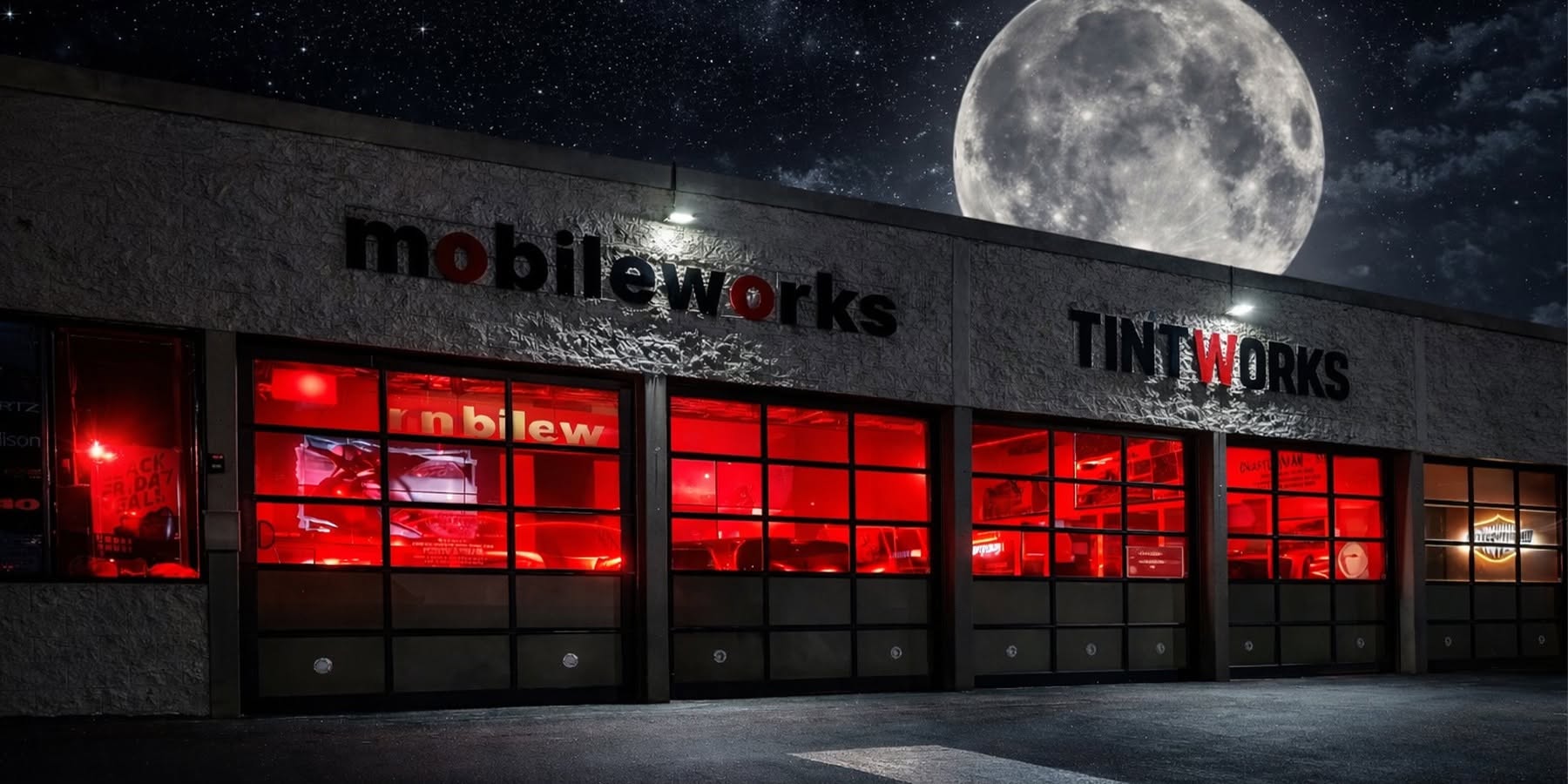 The Mobileworks and Tint works storefront in Santa Maria at night, its service bays glowing red