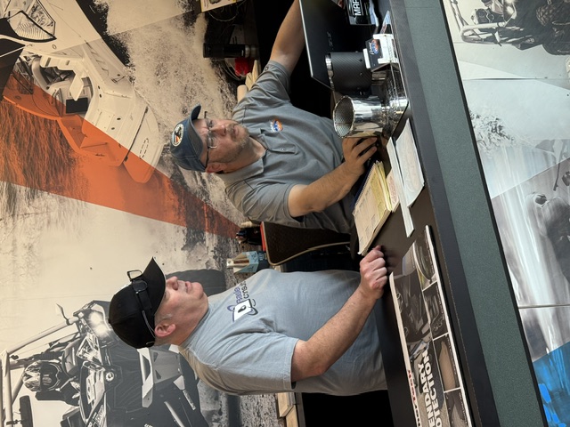 Richard Basler working at the counter alongside a staff member during a migration