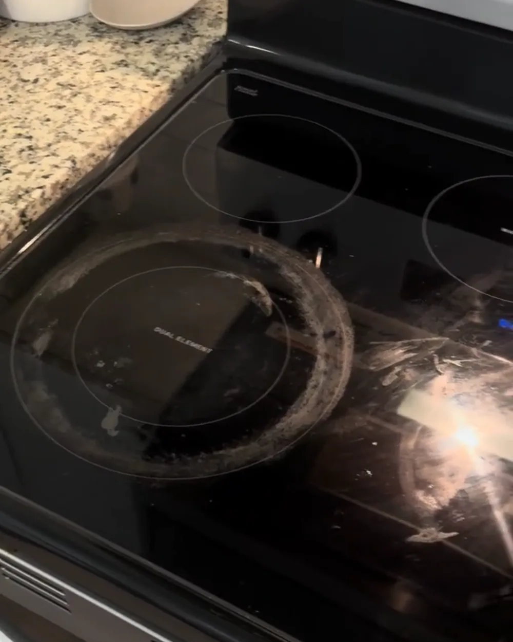 Glass stovetop with heavy burnt-on residue before cleaning