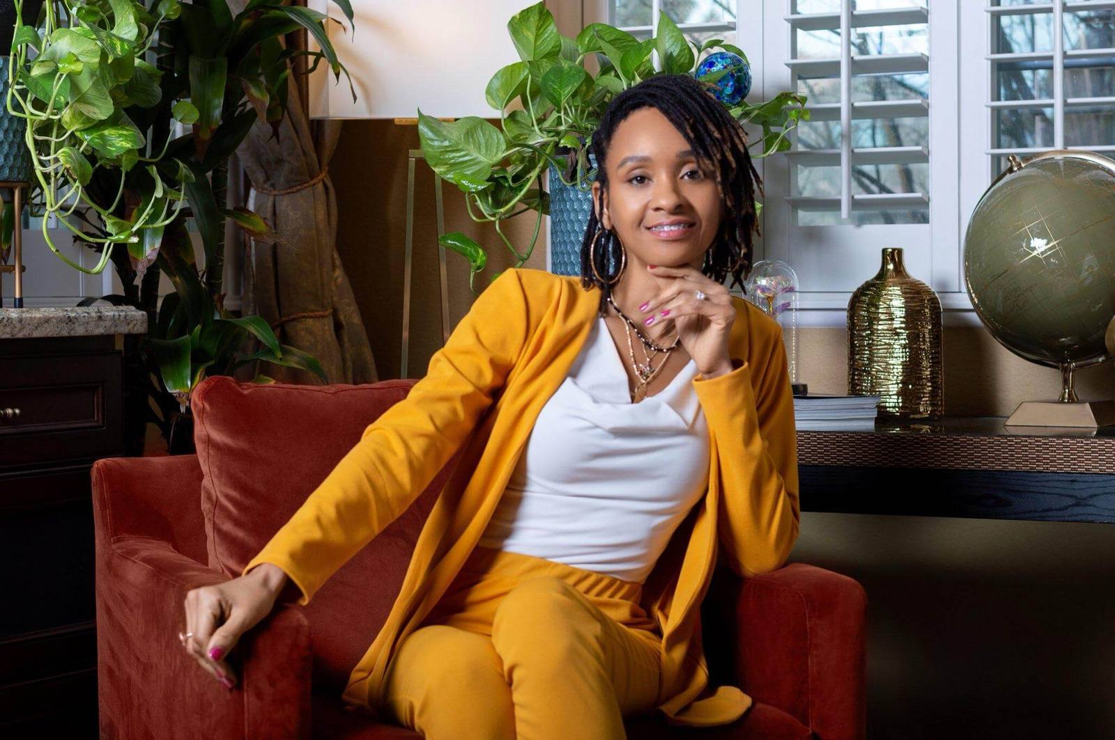 AKimie seated in a warm study wearing a gold suit