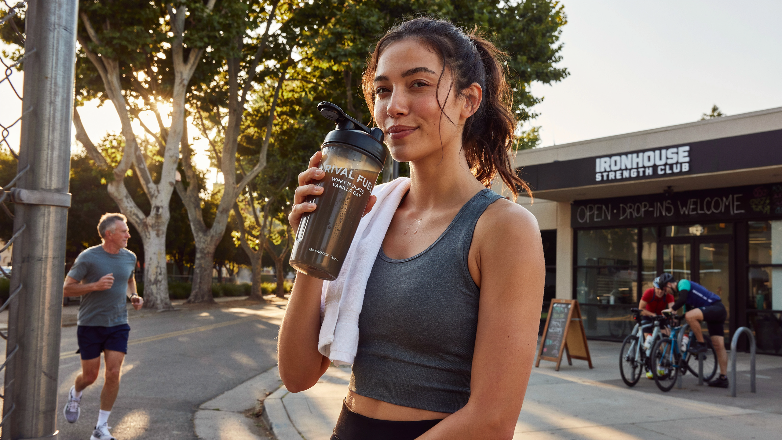 A person in athletic wear post-workout, drinking a protein shake, looking energized and satisfied. Golden hour lighting, outdoor setting near a gym. A person in athletic wear post-workout, drinking a protein shake, looking energized and satisfied. Golden hour lighting, outdoor setting near a gym.