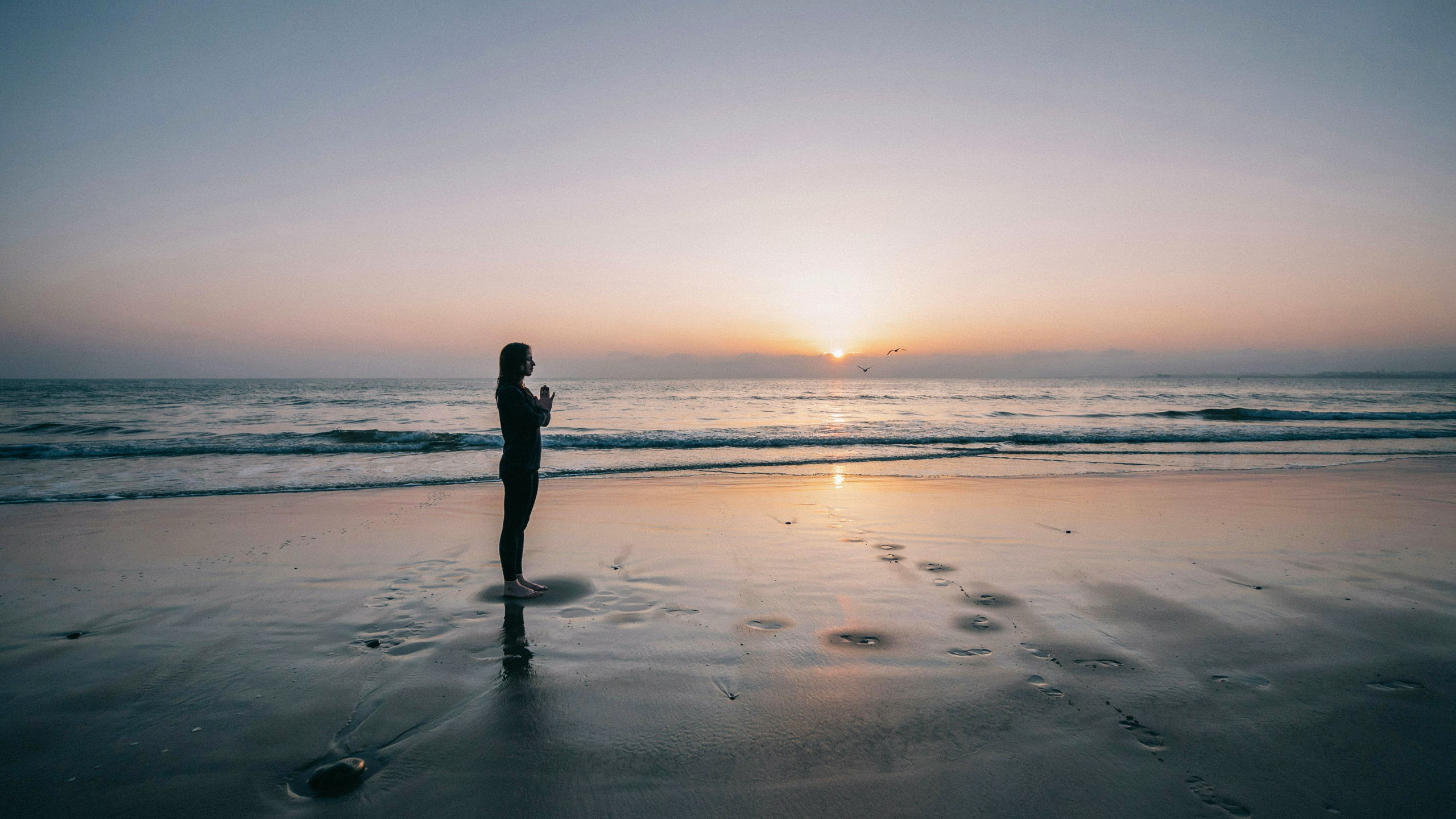 Photorealistic sunrise over a calm ocean, golden light reflecting on water, single person standing on beach in meditation pose, silhouetted figure, sense of new beginning and presence Photorealistic sunrise over a calm ocean, golden light reflecting on water, single person standing on beach in meditation pose, silhouetted figure, sense of new beginning and presence