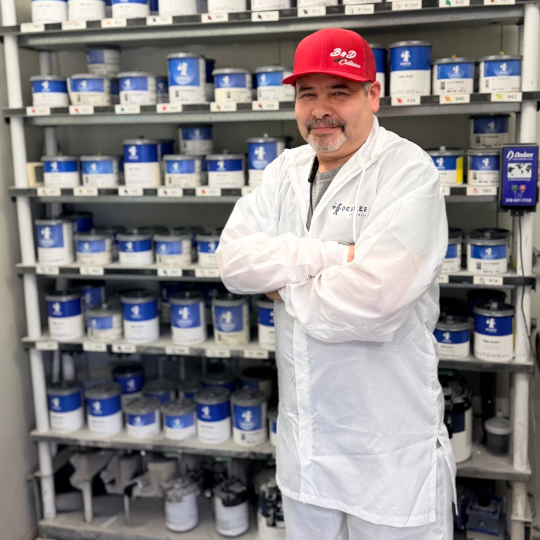 Professional painter at B&D Collision in Mesquite standing in front of paint cans on a rack