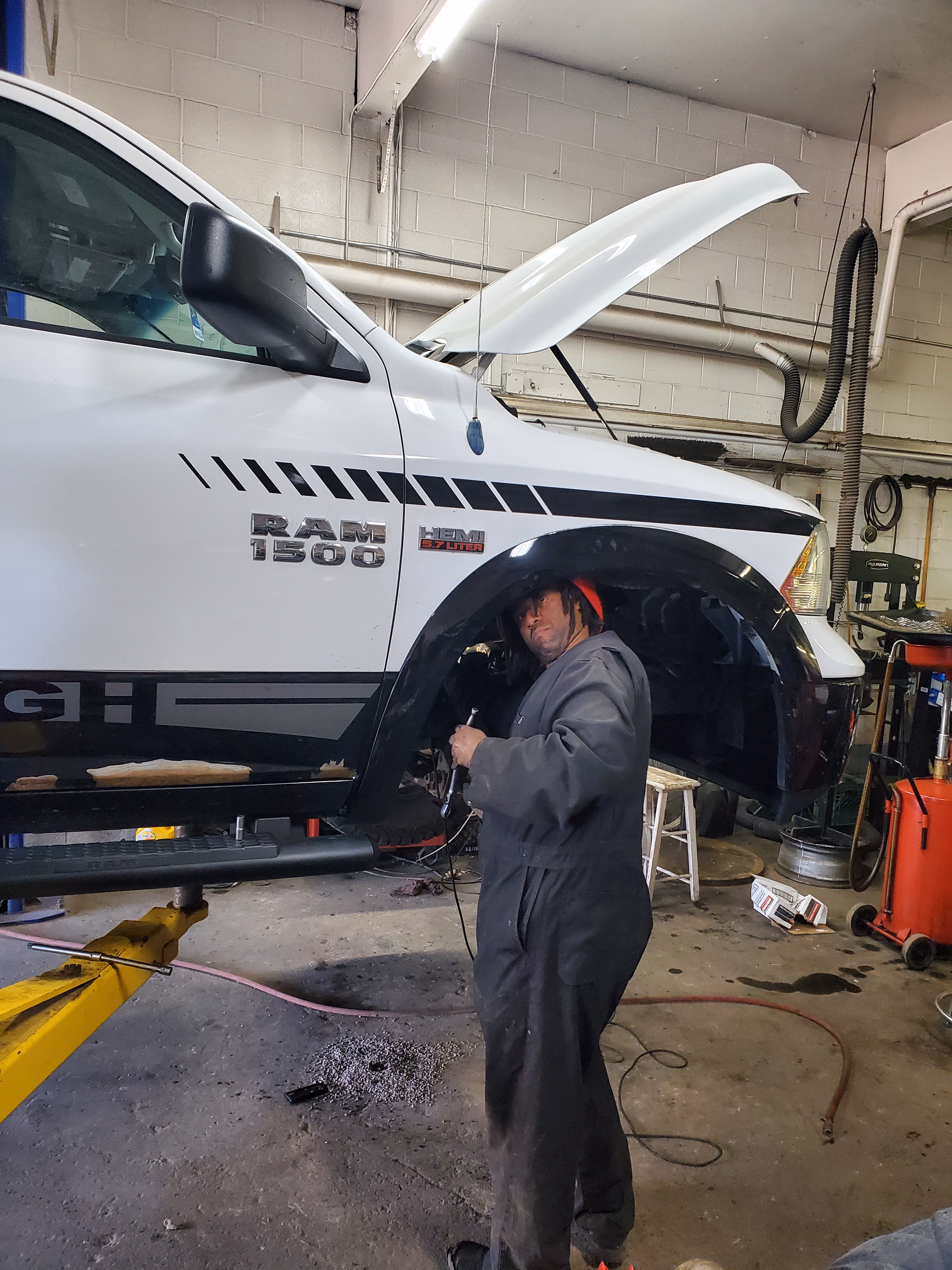 Red Seal mechanic working under a pickup truck on a lift at JCo Auto in SE Calgary
