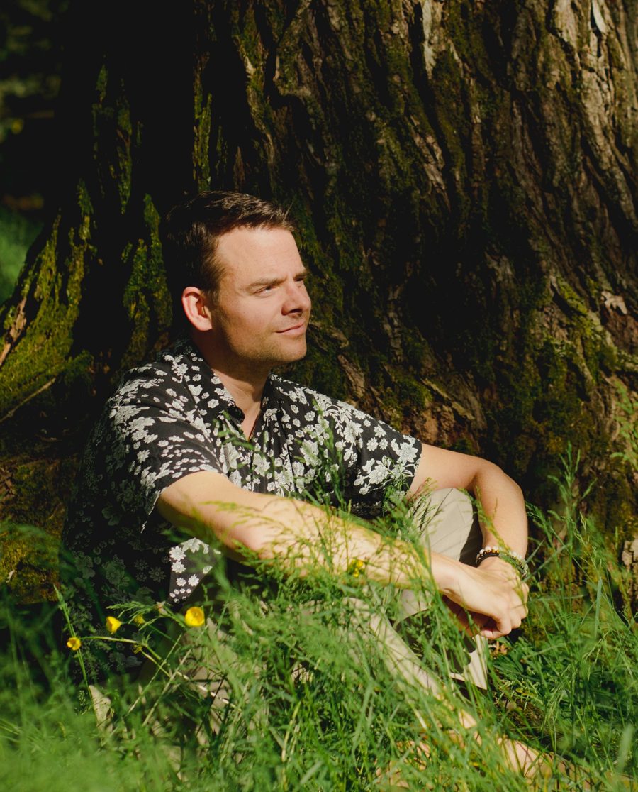 Philipp, im Gras an einen Baum gelehnt