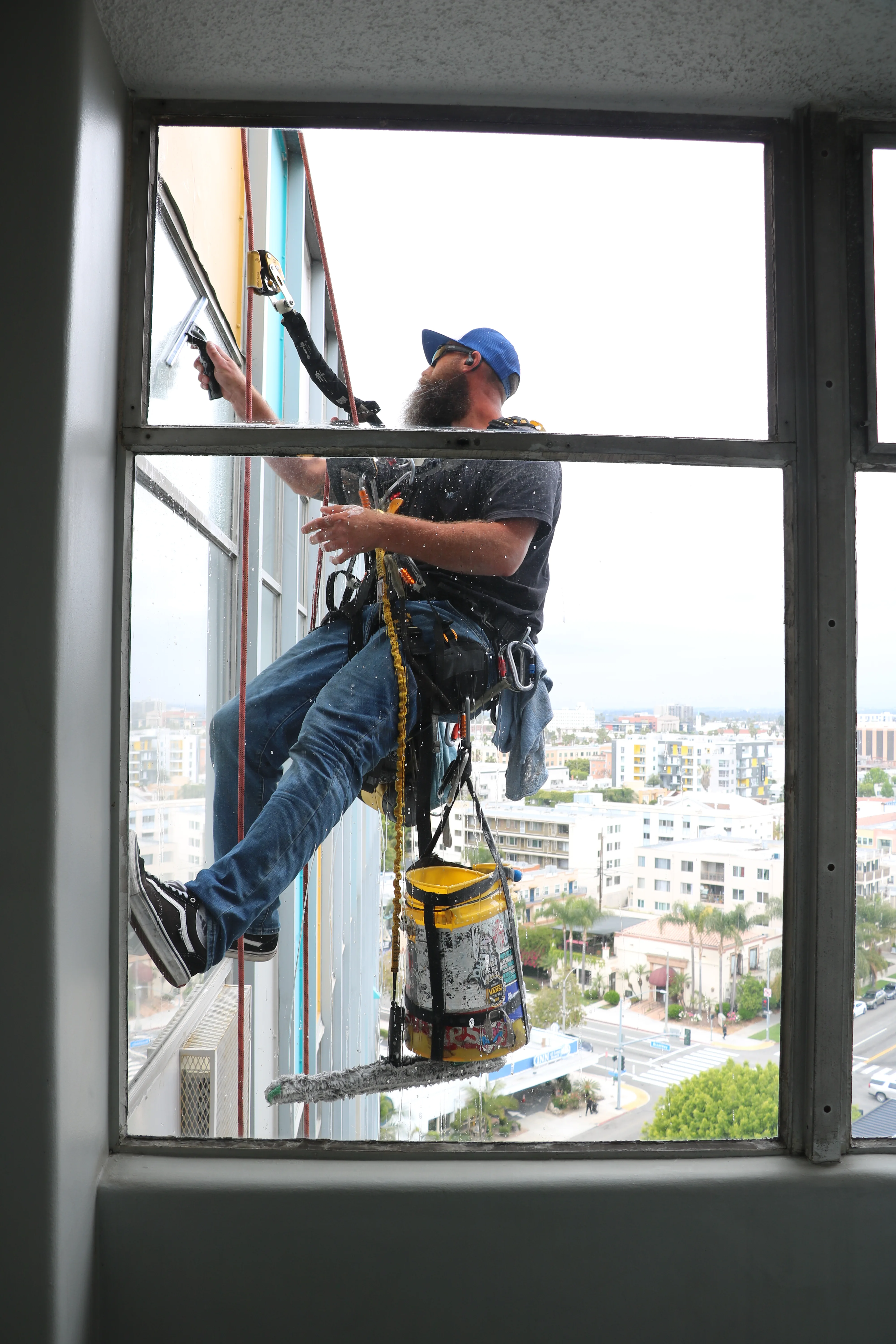 Rope-access technician cleaning exterior building glass