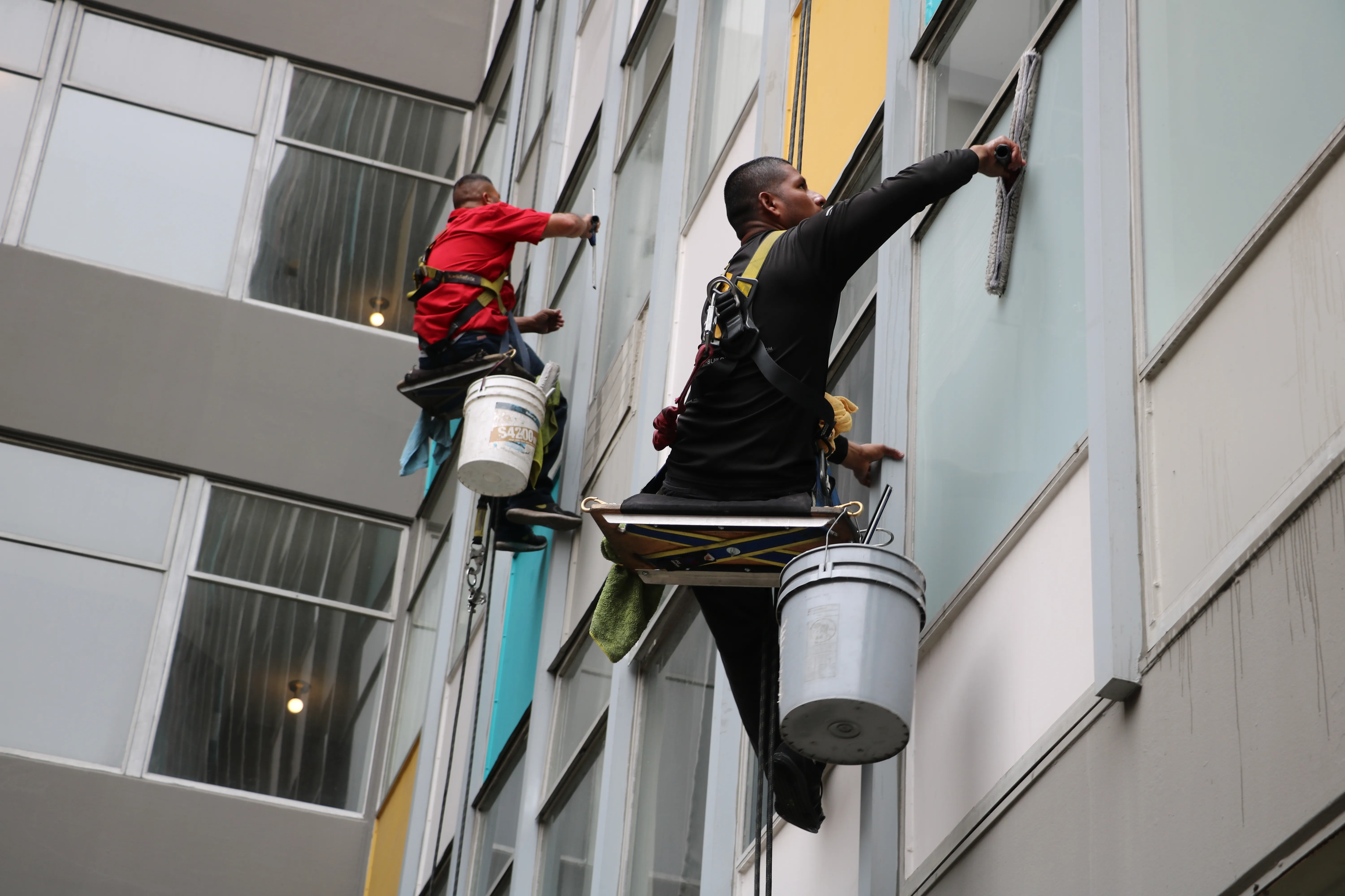 Two rope-access technicians cleaning a commercial facade