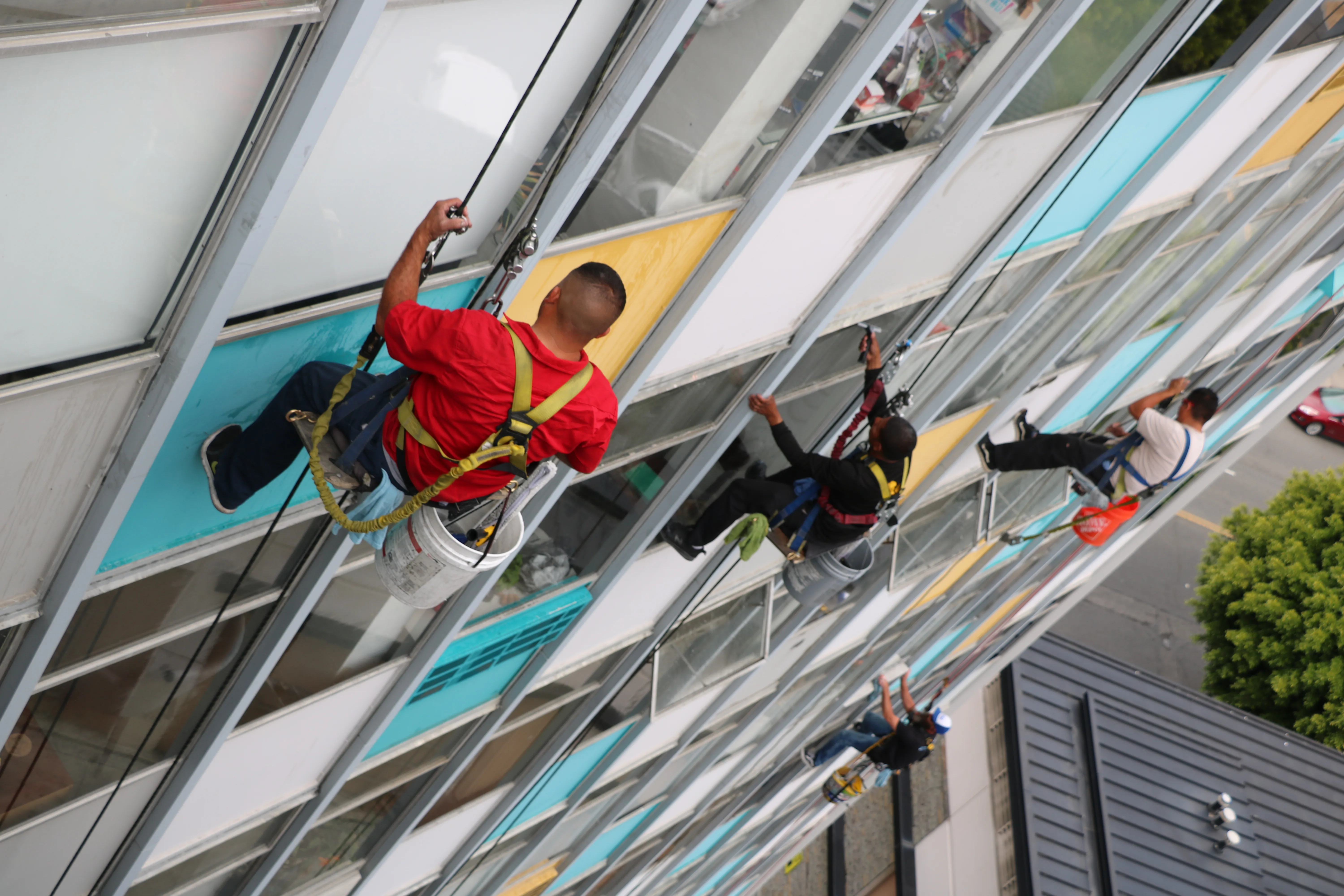 Several rope-access technicians cleaning a commercial facade
