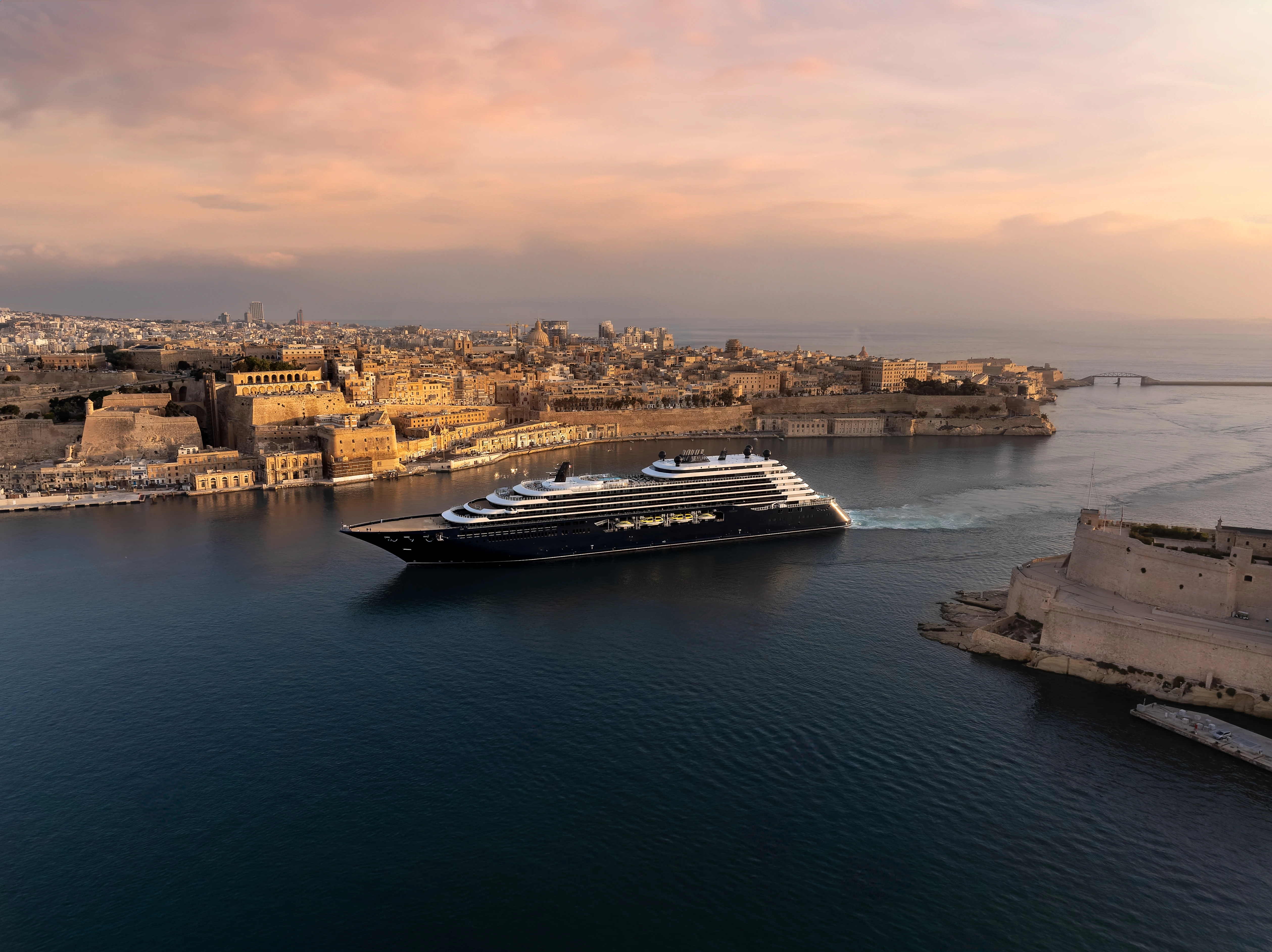 Luxury yacht sailing along a coastal destination at sunset