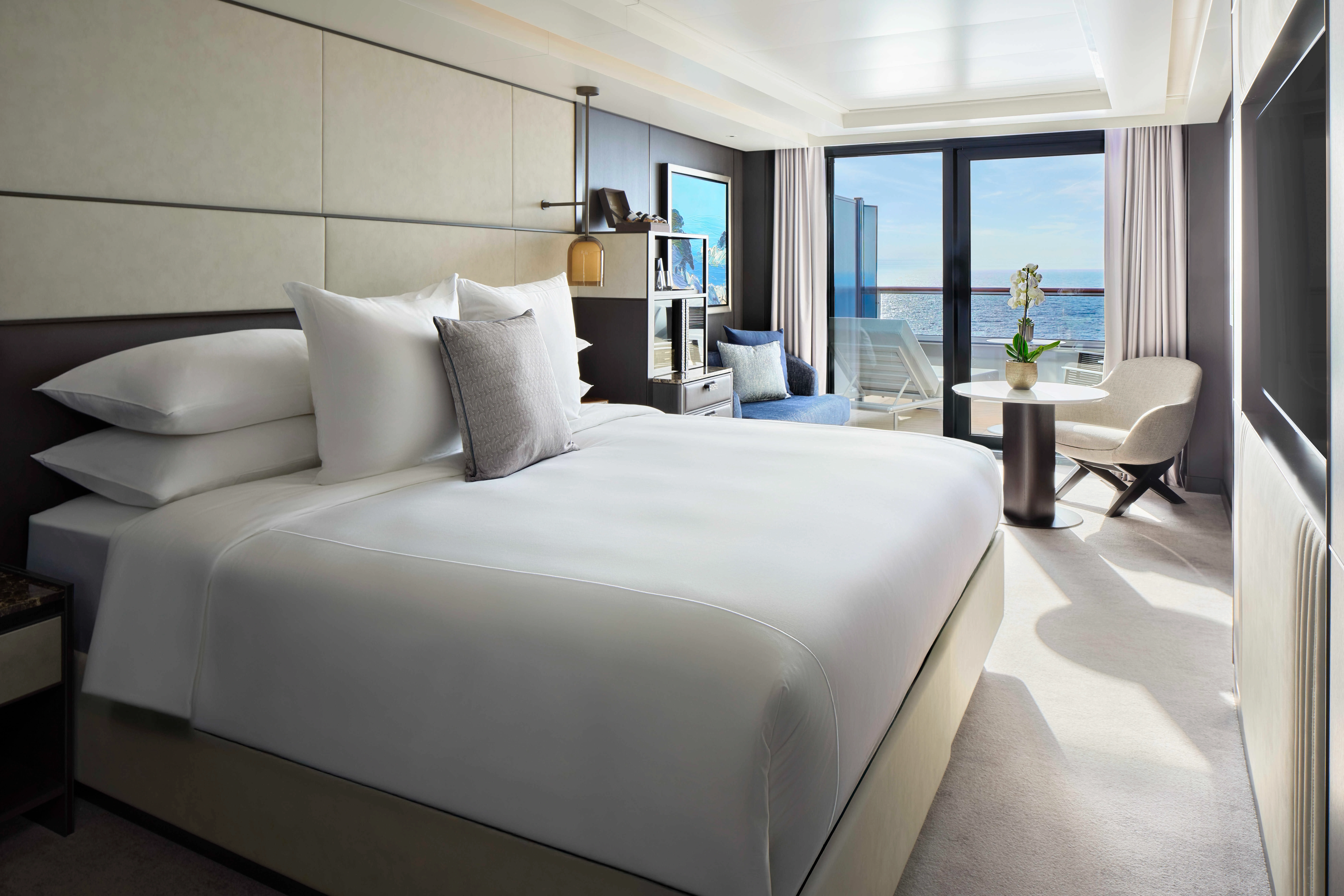 Spacious luxury yacht suite opening onto a private ocean-view balcony