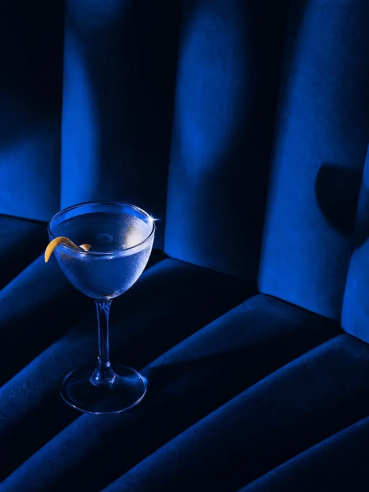 A coupe glass on a blue velvet banquette
