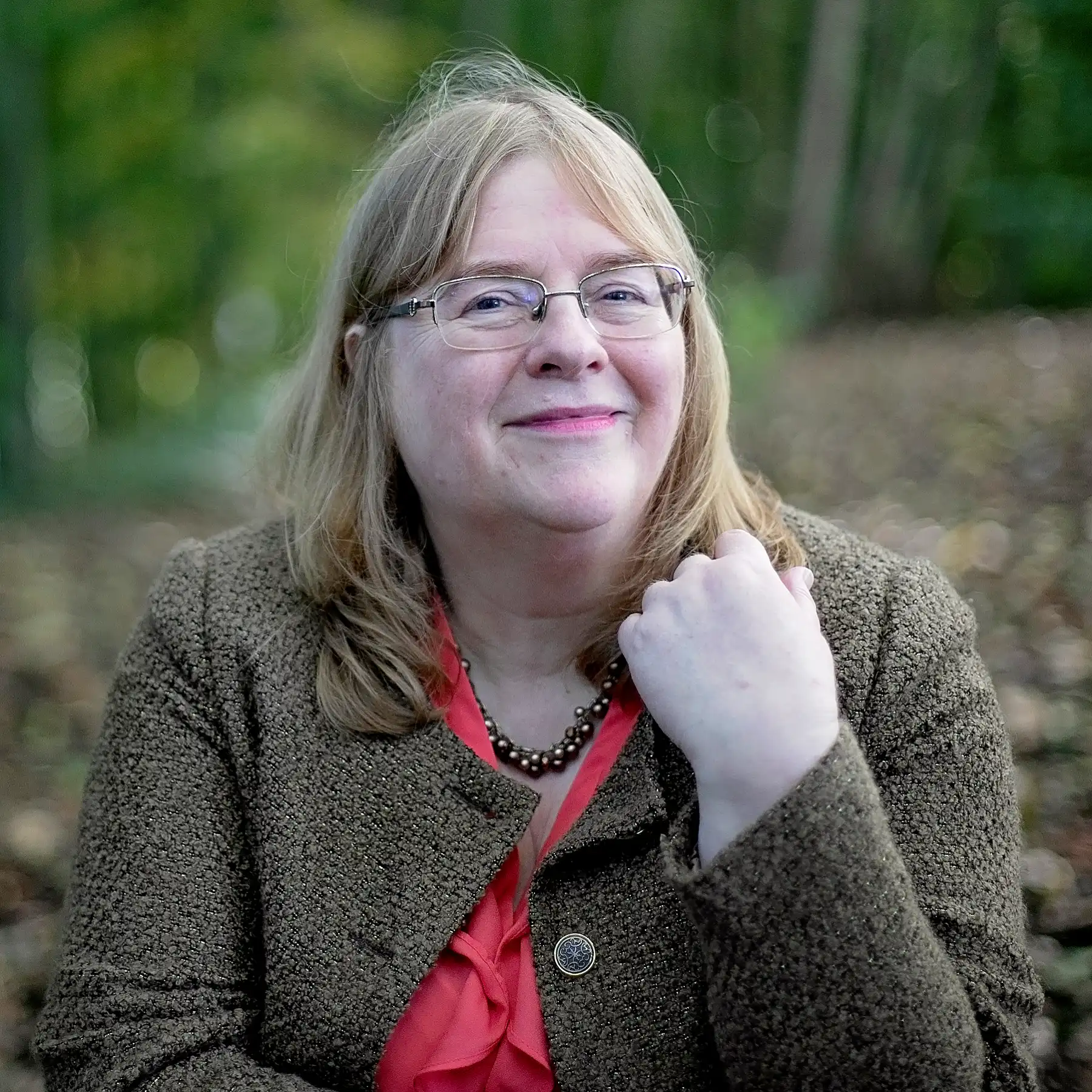 Kathryn Dunn, cognitive behavioural hypnotherapist, in a coral top and green jacket