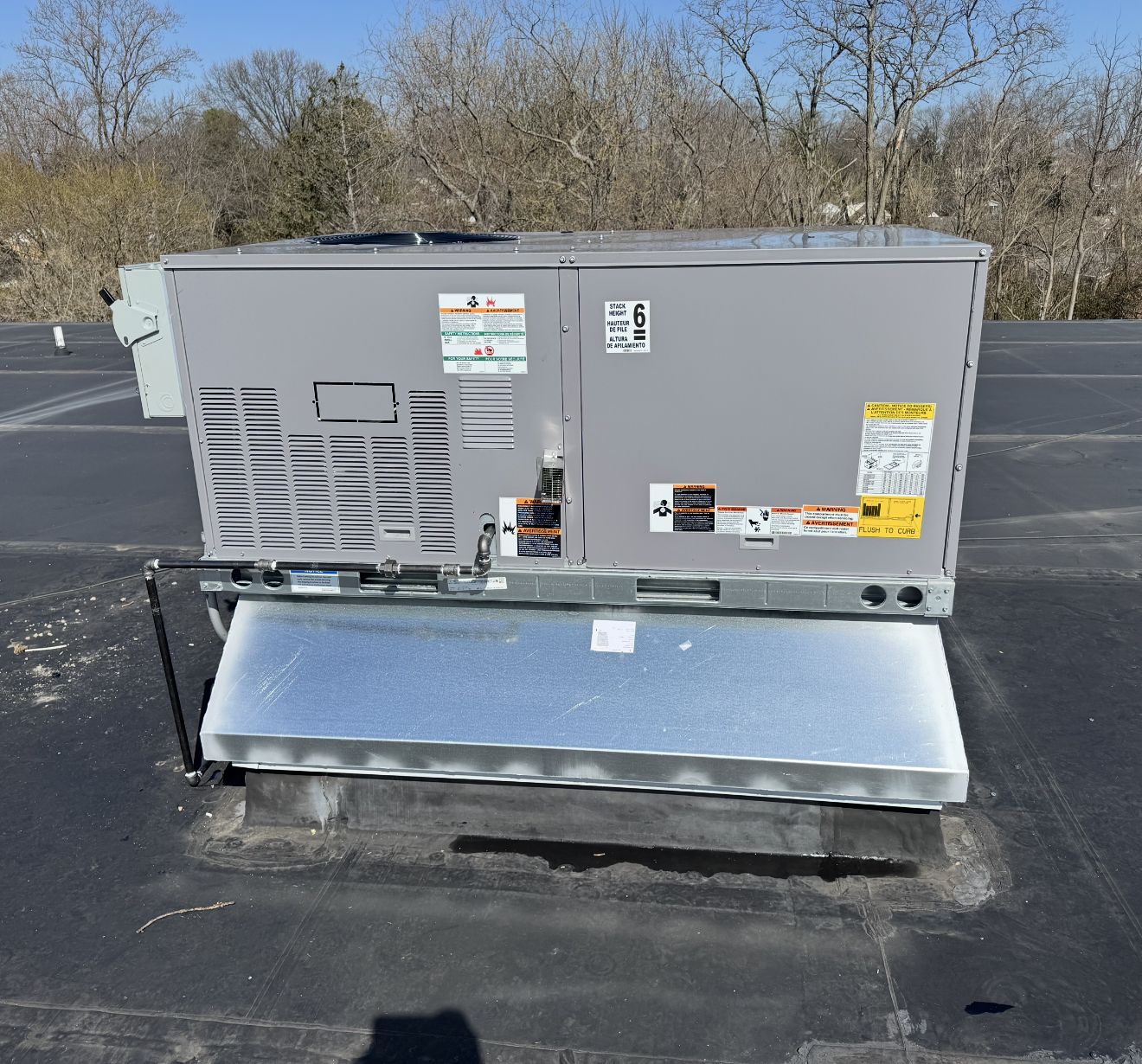 Commercial packaged rooftop HVAC unit sitting on a roof curb