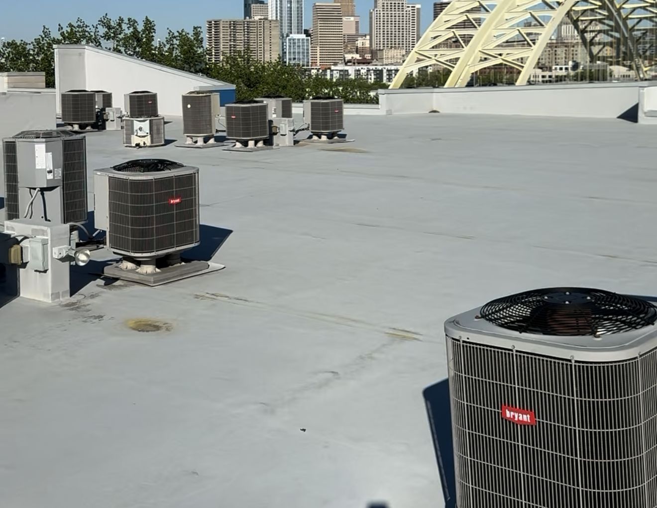 Rooftop condensing units with the Cincinnati skyline and a yellow arch bridge in the background