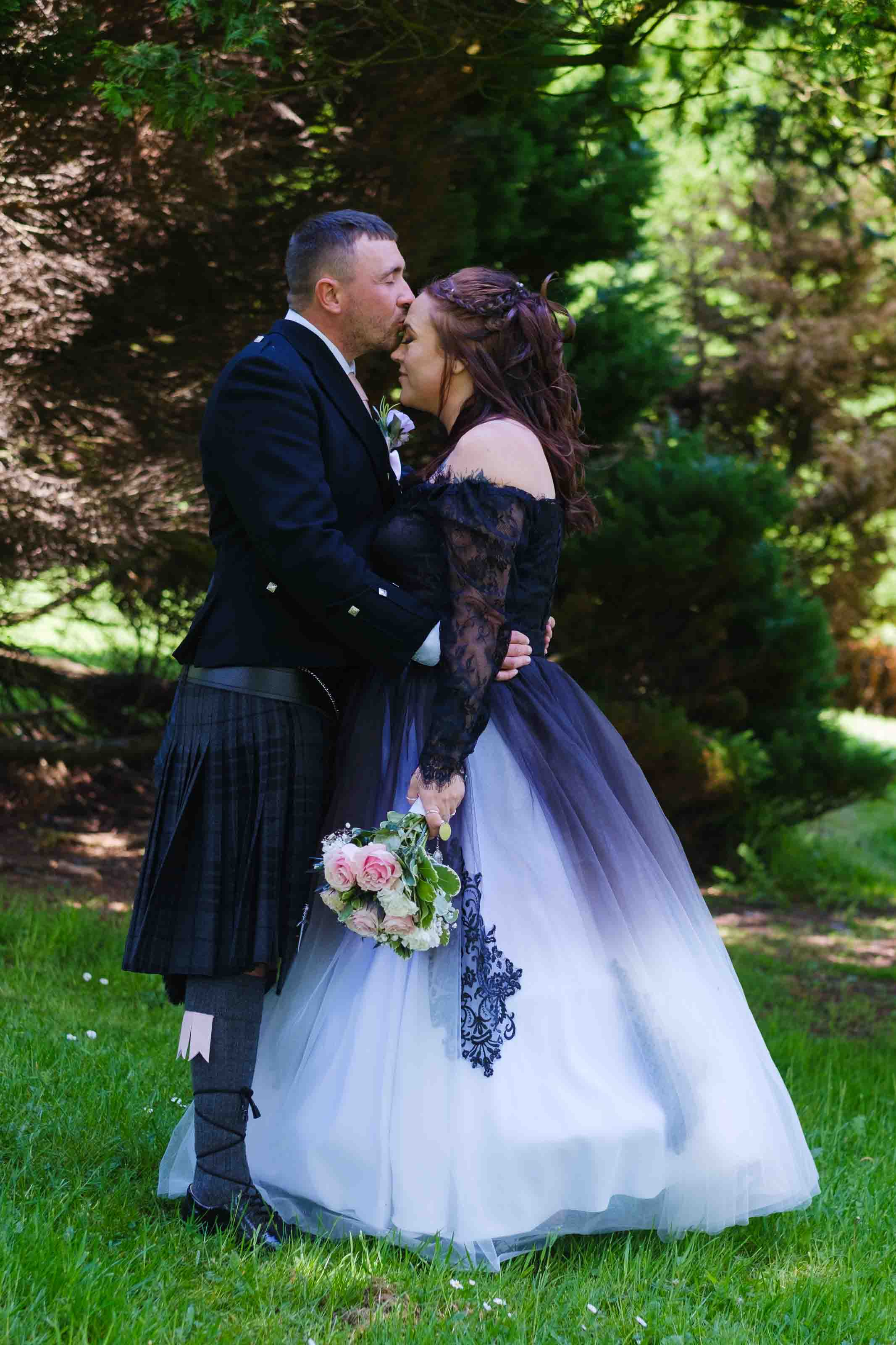 Relaxed wedding photography in Scotland, groom kissing bride's head in Kay Park, Kilmarnock