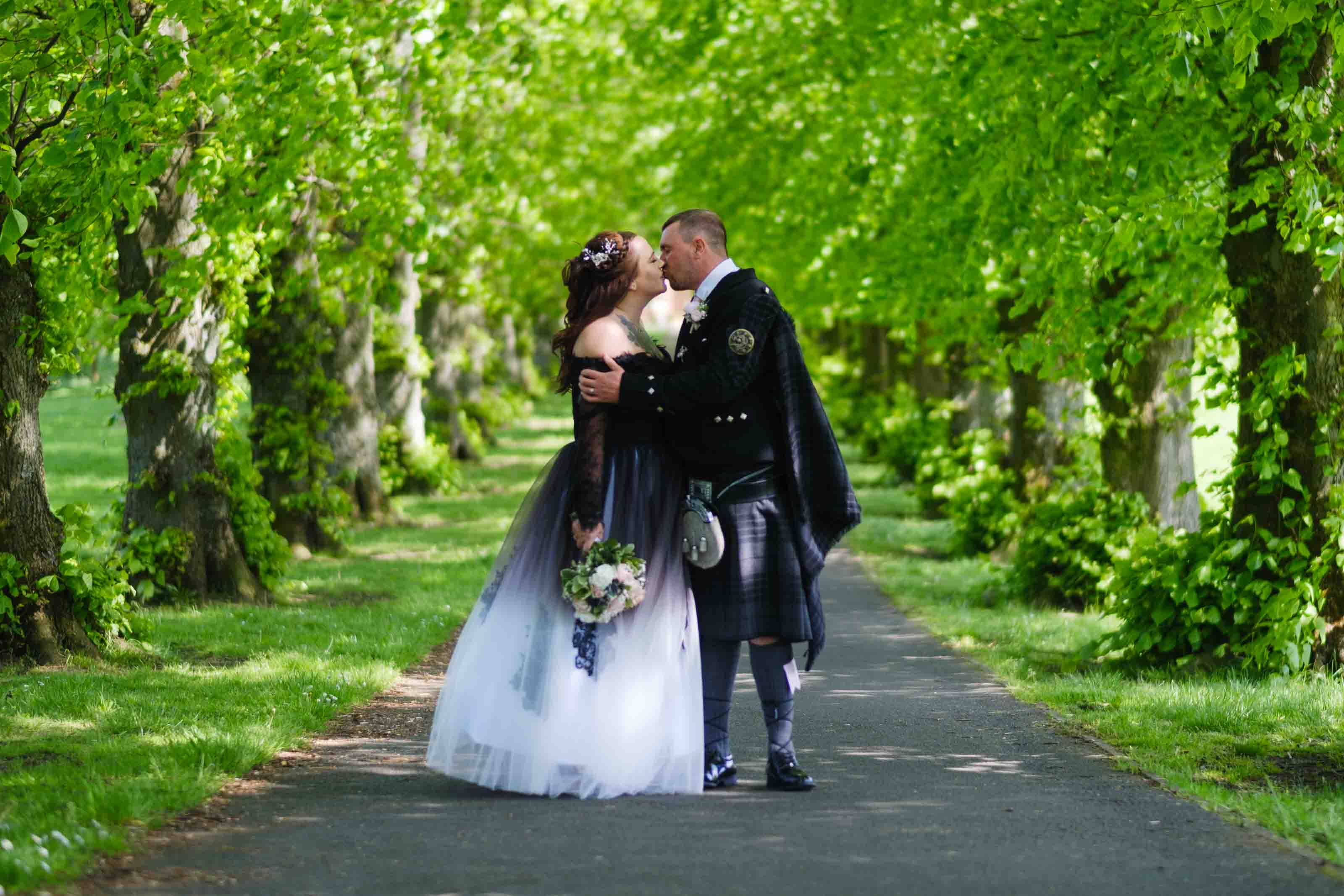 Natural wedding portraits in Ayrshire, newly married bride and groom kissing in Kay Park, Burns Monument, Kilmarnock