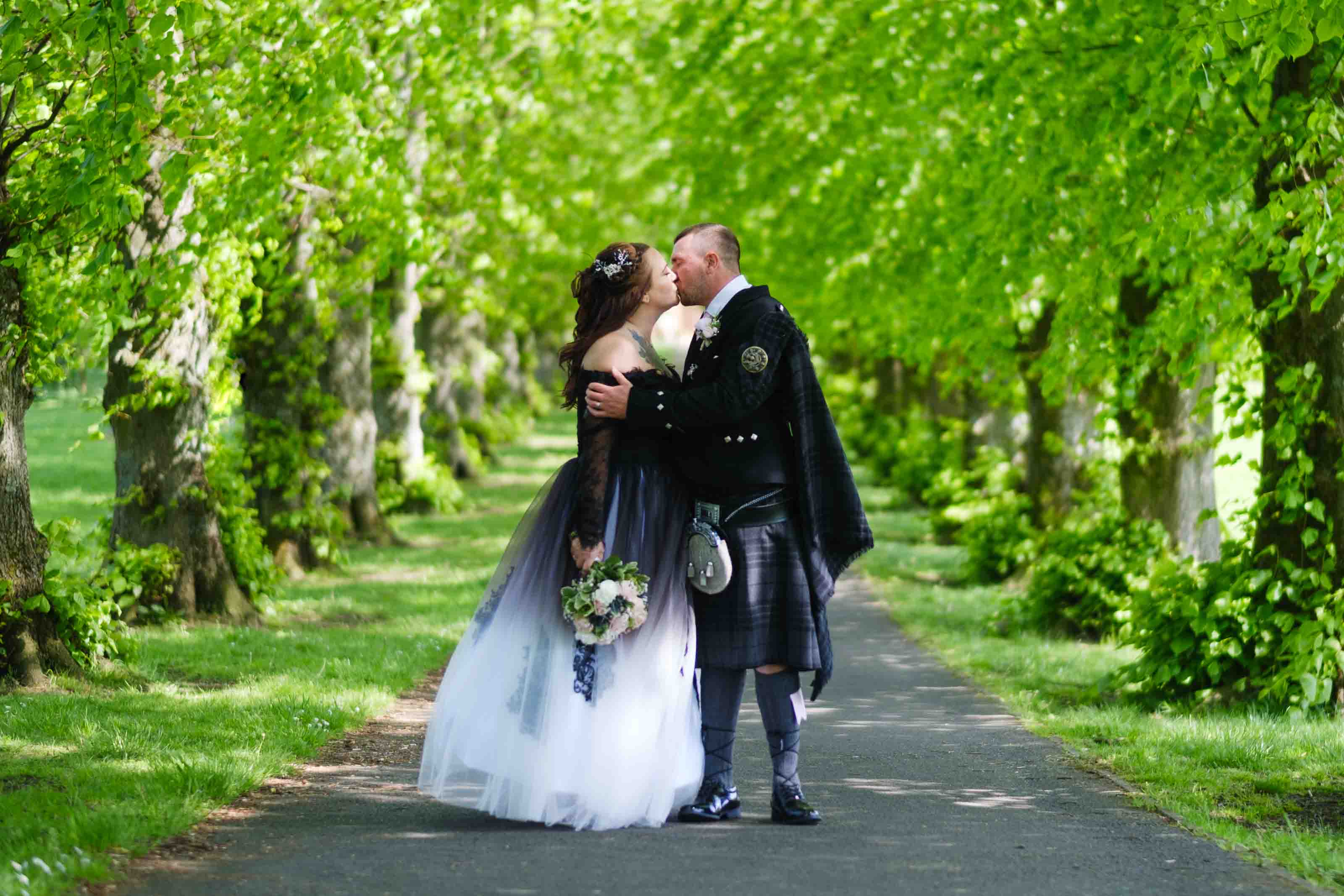 Newly married couple kissing after looking at their wedding rings. The Burns Monument Centre, Kay Park, Kilmarnock