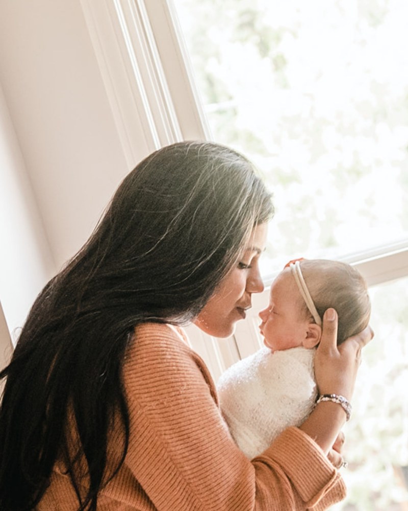 Mother holding her newborn by a sunlit window