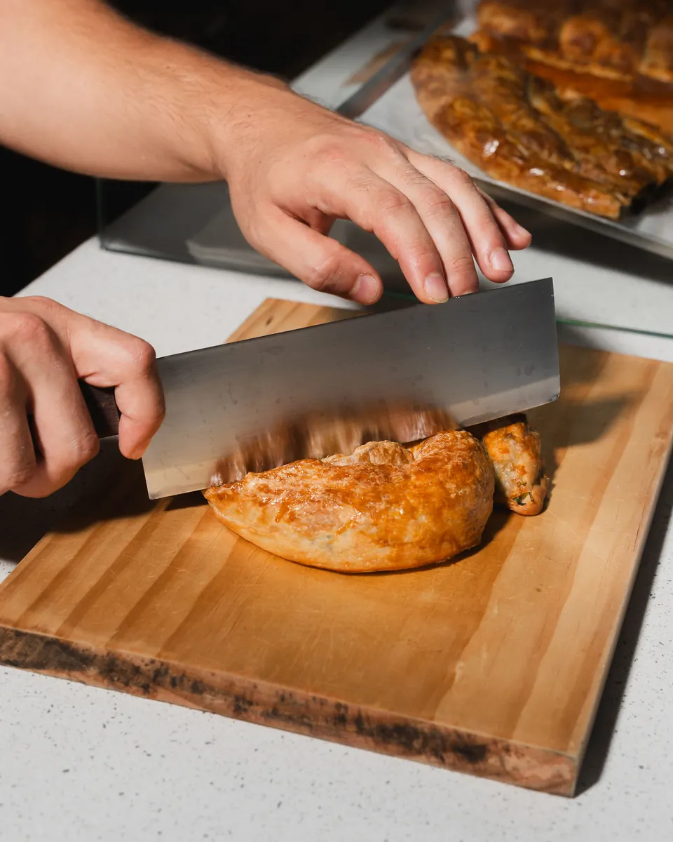 Freshly baked börek being sliced on a wooden board