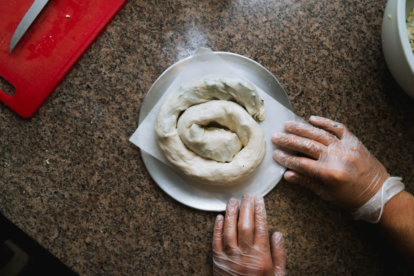 Hands coiling fresh börek dough into a rose spiral in the Rose Borek kitchen