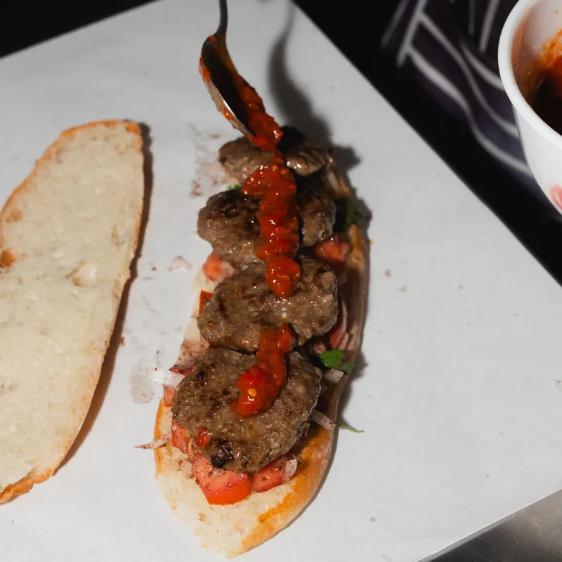 Homemade köfte roll with chilli sauce on Turkish bread