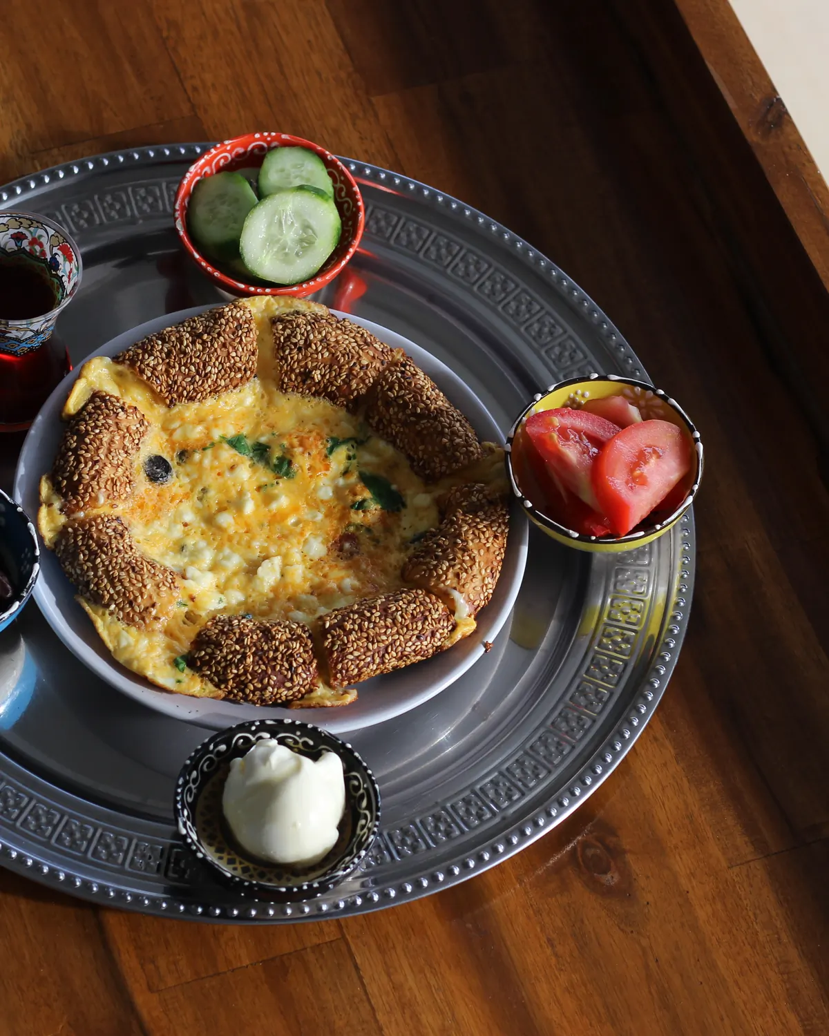 Turkish breakfast tray with simit-ringed eggs, olives, tomato, cucumber and kaymak