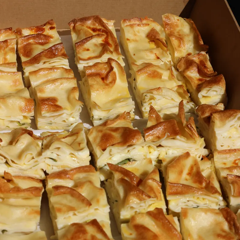 Box of golden cheese börek squares, fresh from the oven
