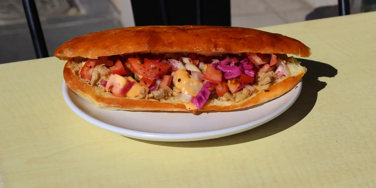 Turkish bread loaded with chicken, tomato, pickled cabbage and sauce