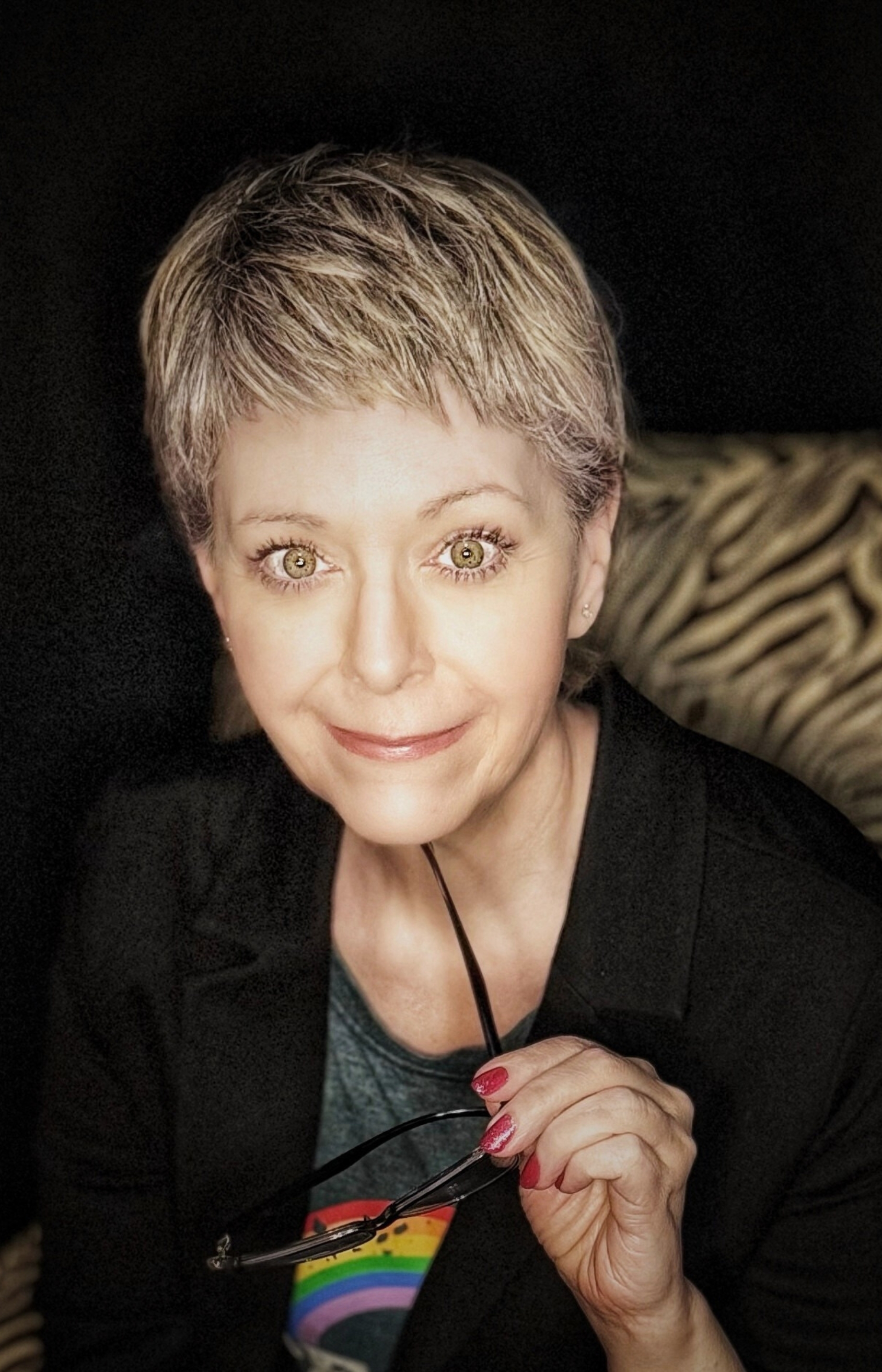 Tracy Quinlan, author, writer, Acutonics sound healing practitioner, and Astrologer in Edmonton, Alberta, Canada, smiling and holding her glasses.