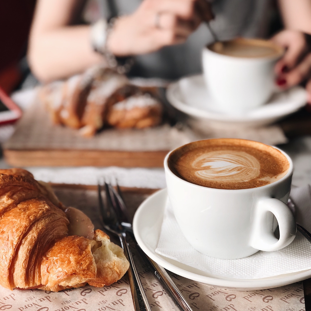 A latte and a croissant on a café table
