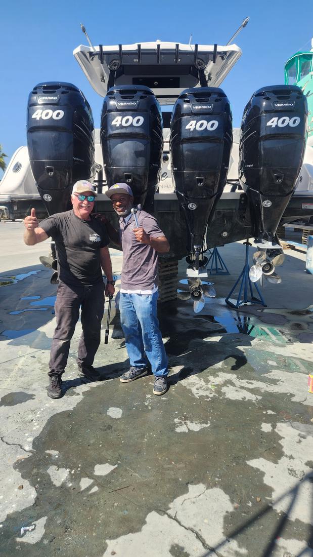 Marine technician giving a thumbs up beside a freshly serviced boat