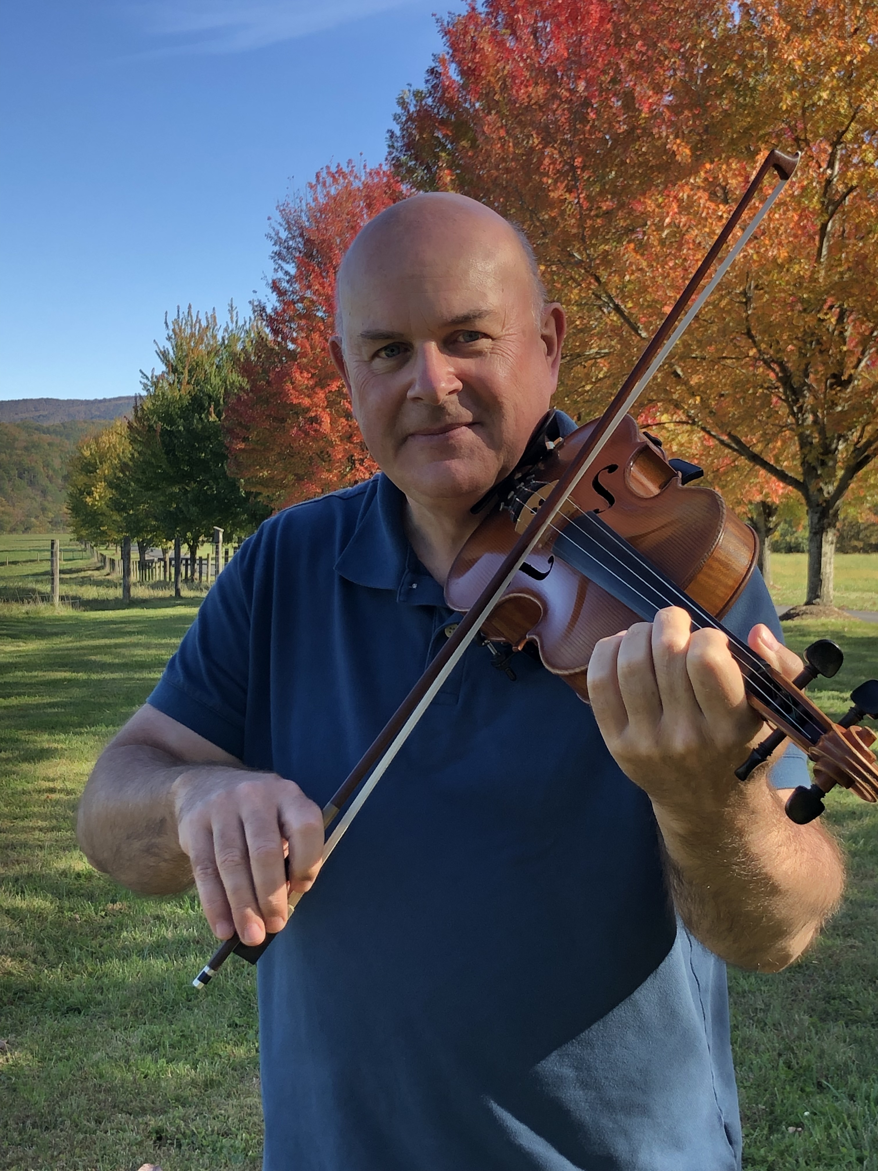 Colin playing fiddle among autumn trees in the Highlands of Virginia