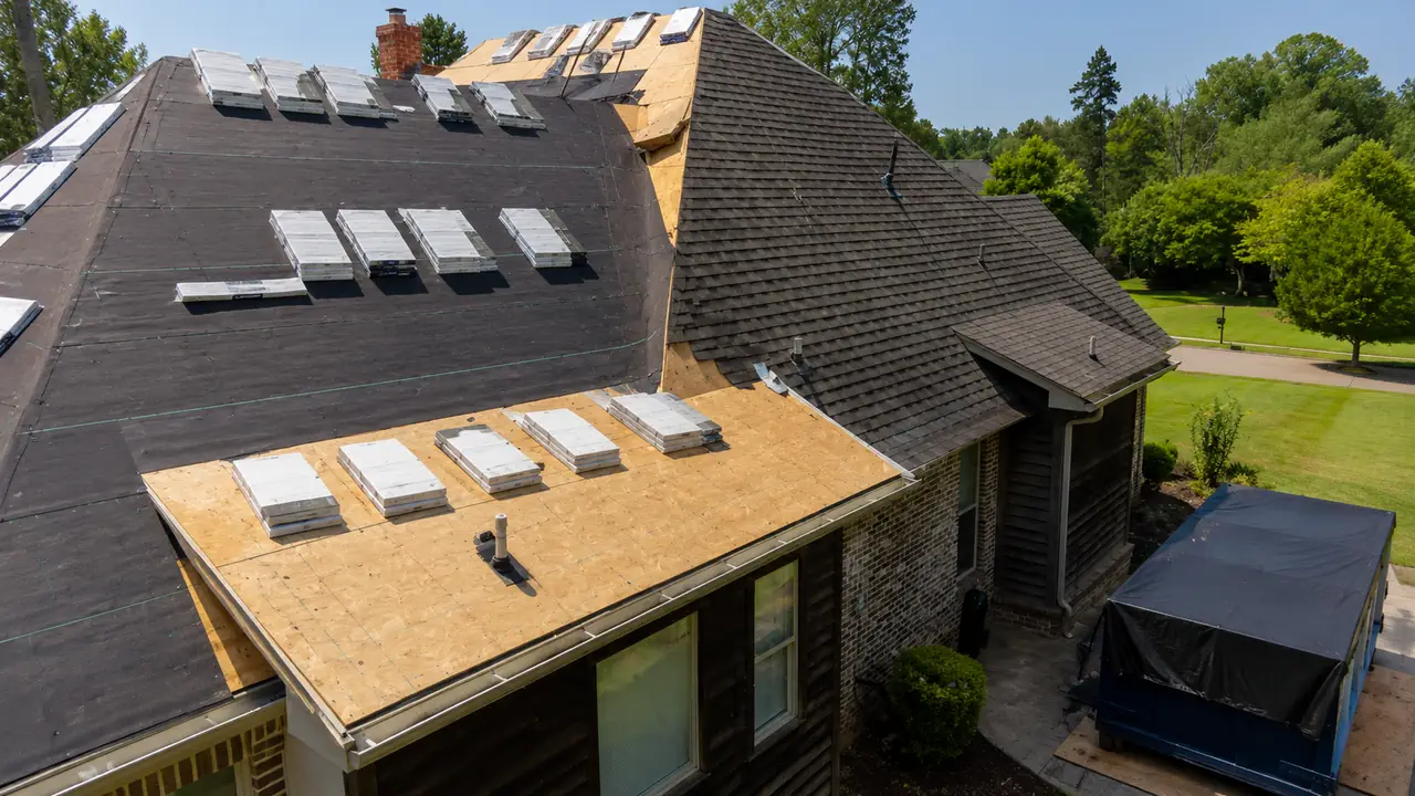Roofing team completing full roof replacement on upscale Bellevue Washington home with new dark shingles