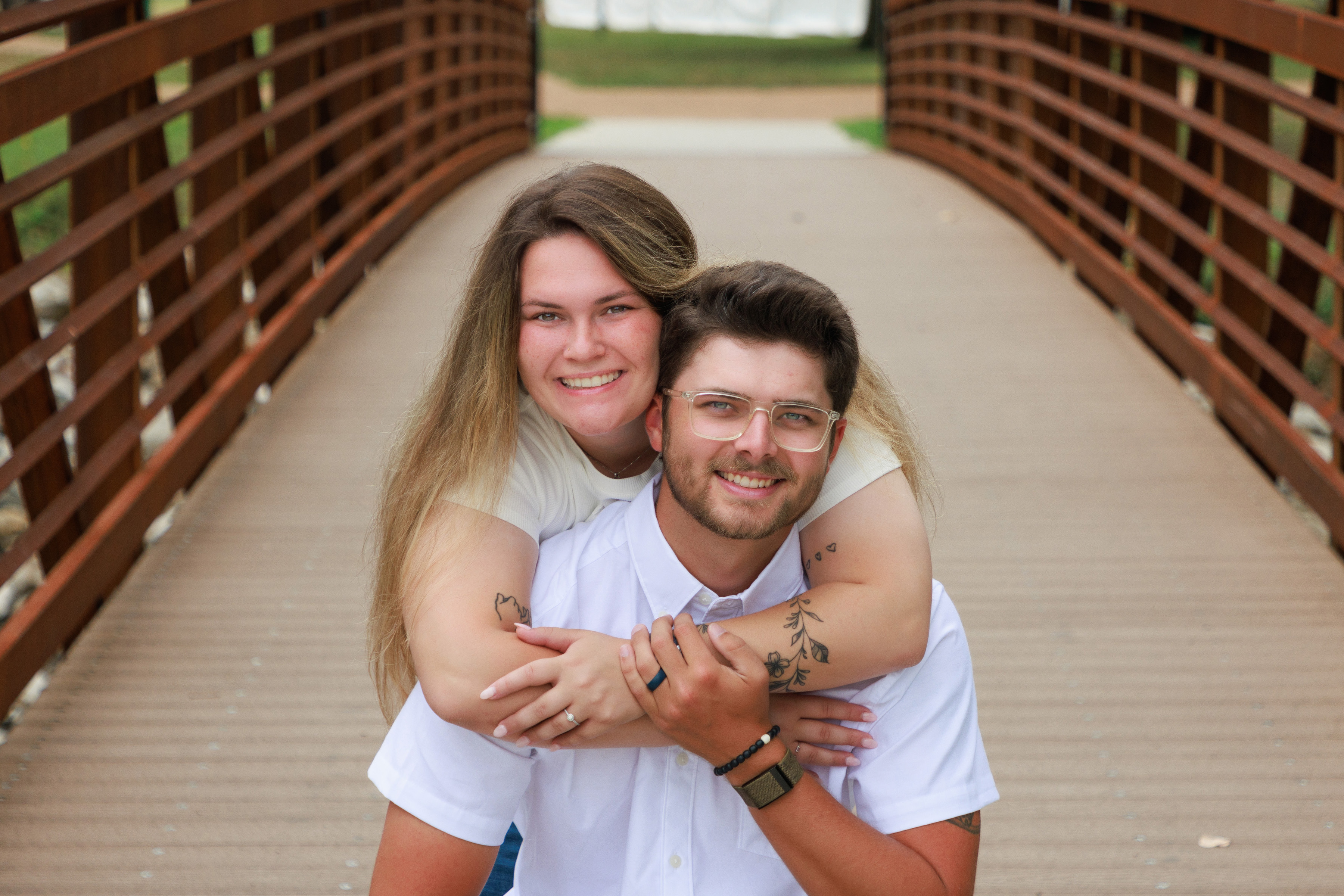 Smiling couple hugging on a wooden footbridge during their engagement session