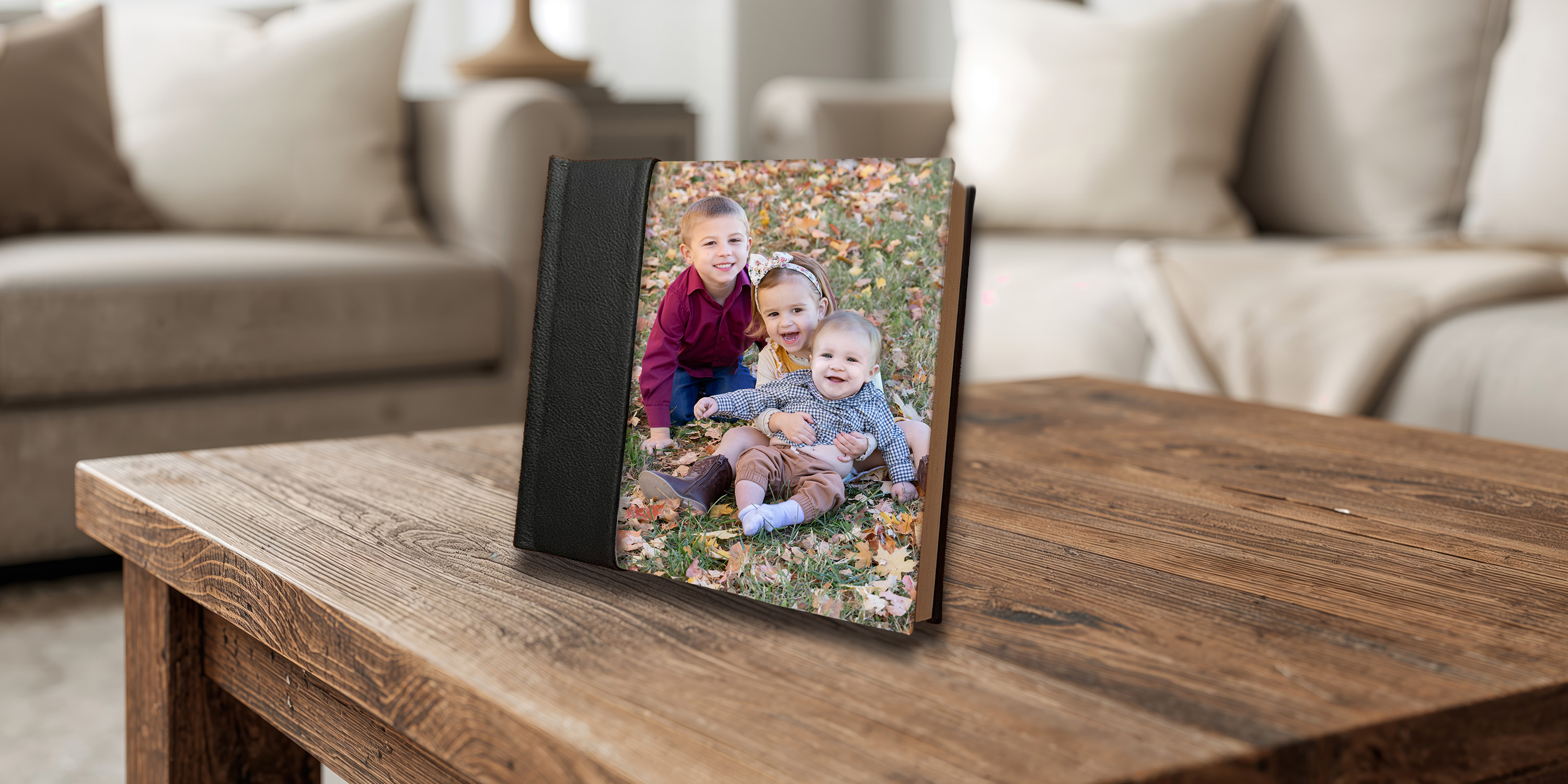 Heirloom photo album with a sibling portrait on the cover, displayed on a rustic wood coffee table