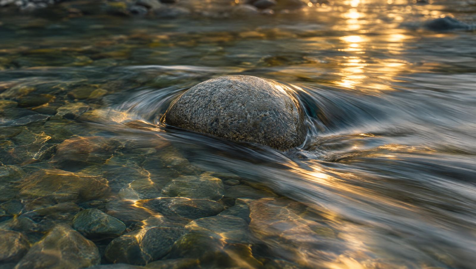 Clear water flowing around a smooth stone