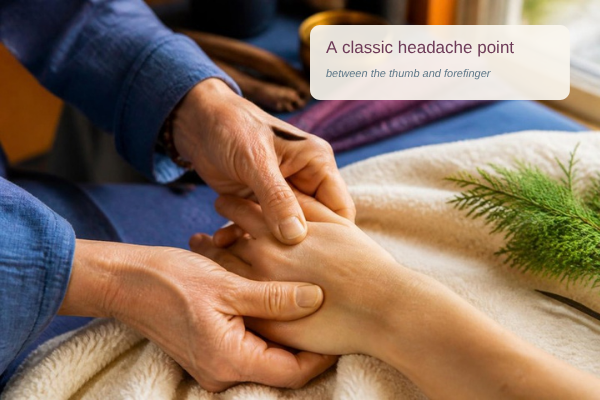 Practitioner pressing the classic headache point between the thumb and forefinger