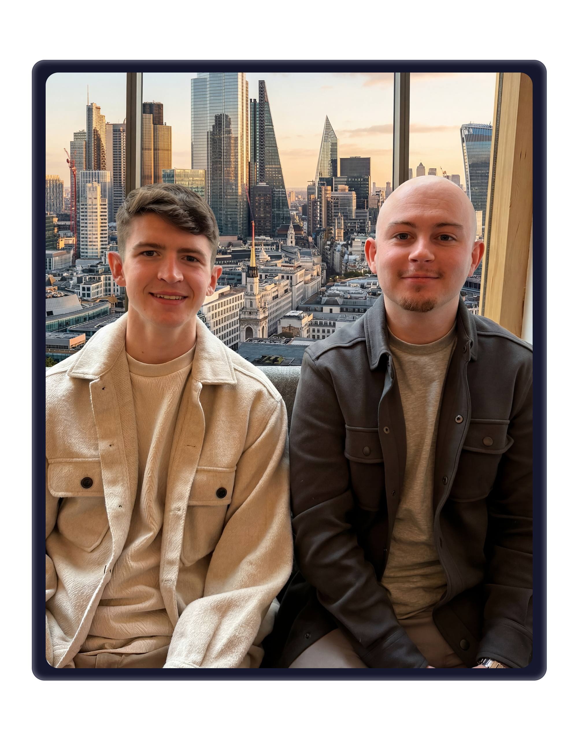 Two men sitting side-by-side in front of a large window with the London skyline and skyscrapers visible in the background.