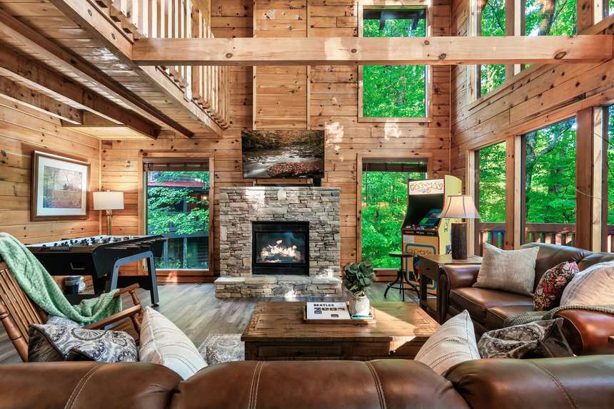 Rockstar Retreat great room with stone fireplace, arcade and forest views