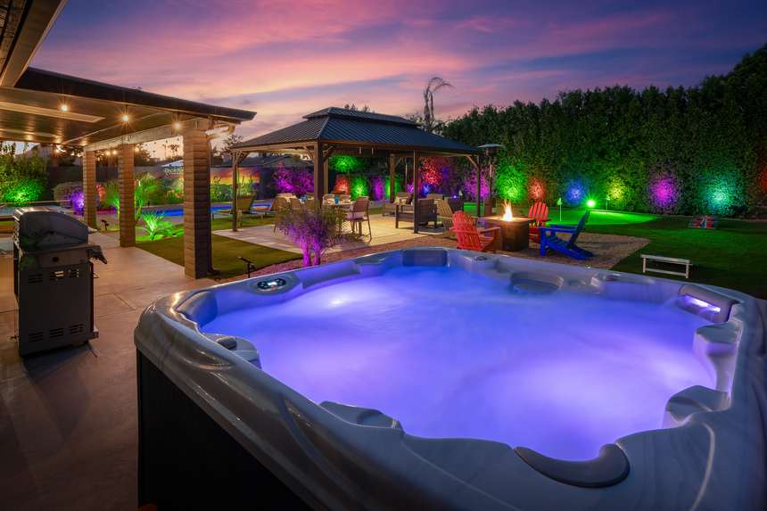 Rockstar Paradise resort backyard at dusk with lit hot tub, gazebo and fire pit