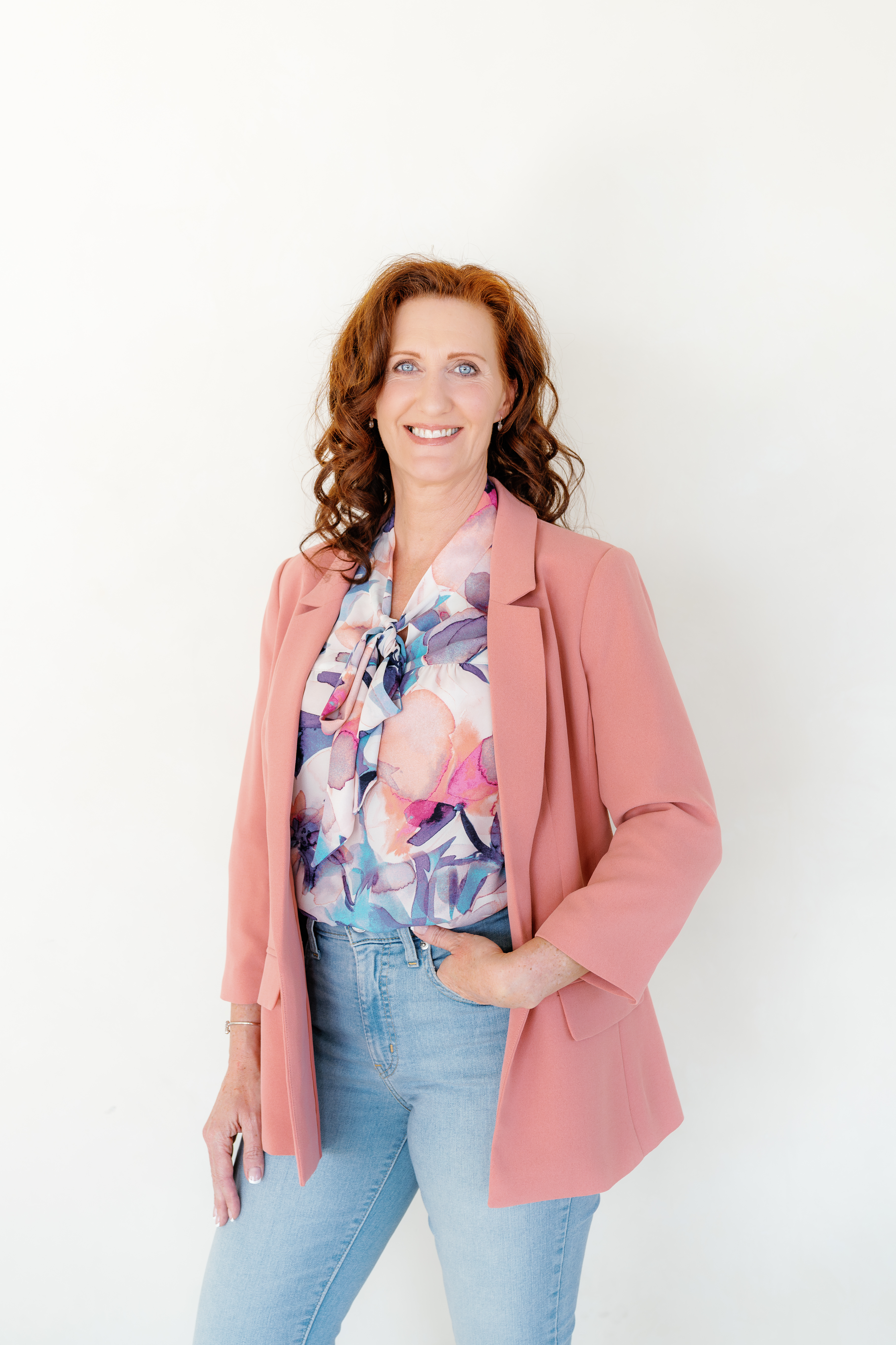 Heather Hickson smiling confidently in a pink blazer, standing against a light background.