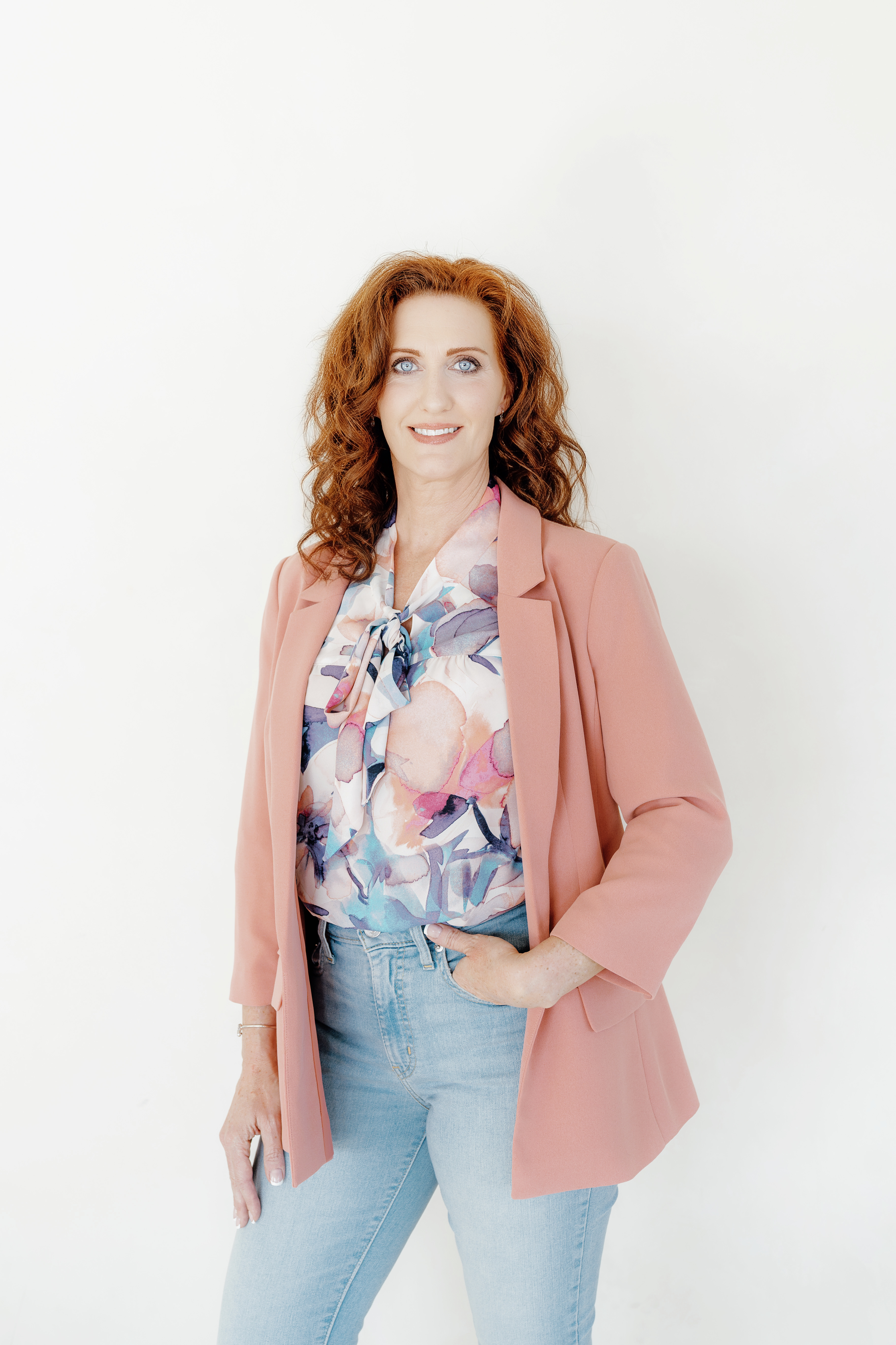 Heather Hickson smiling confidently in a pink blazer, standing against a light background.