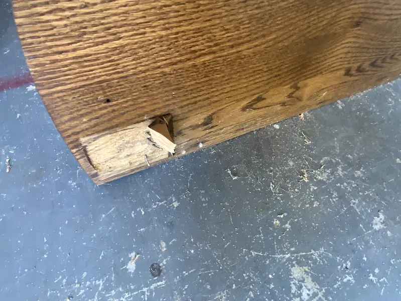 Before photo of a furniture frame with a broken corner leg, prior to repair.
