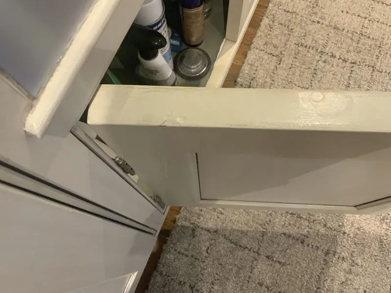 Before photo of a cabinet door with gouges along the top edge, prior to repair.