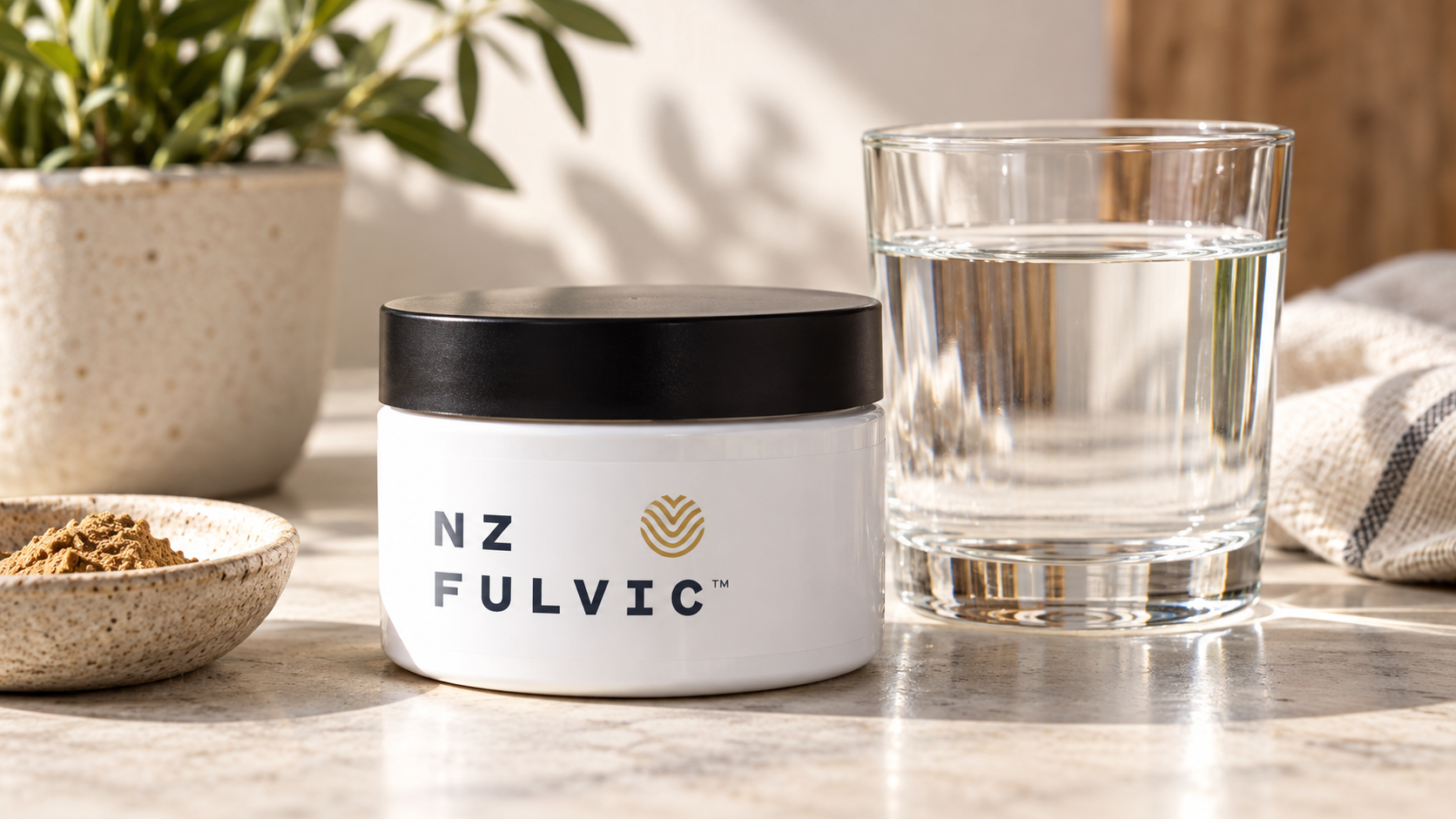 NZ Fulvic powder jar beside a glass of water