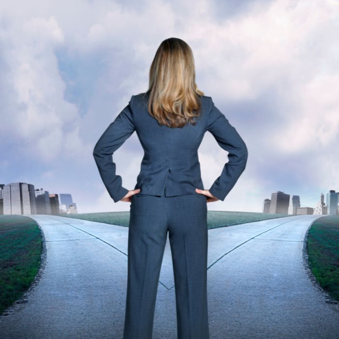 Woman standing at a fork in a natural path representing the moment of choosing between the voice of fear and the quiet knowing of intuition. Woman standing at a fork in a natural path representing the moment of choosing between the voice of fear and the quiet knowing of intuition.