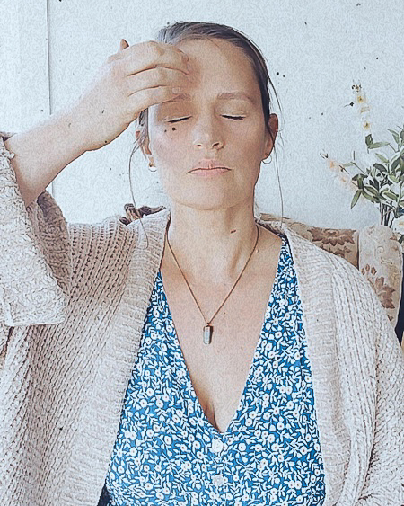 Bright coloured photo of Shannon Neill, EFT Practitioner.  Seated position, eyes closed, and tapping on the right eyebrow point.