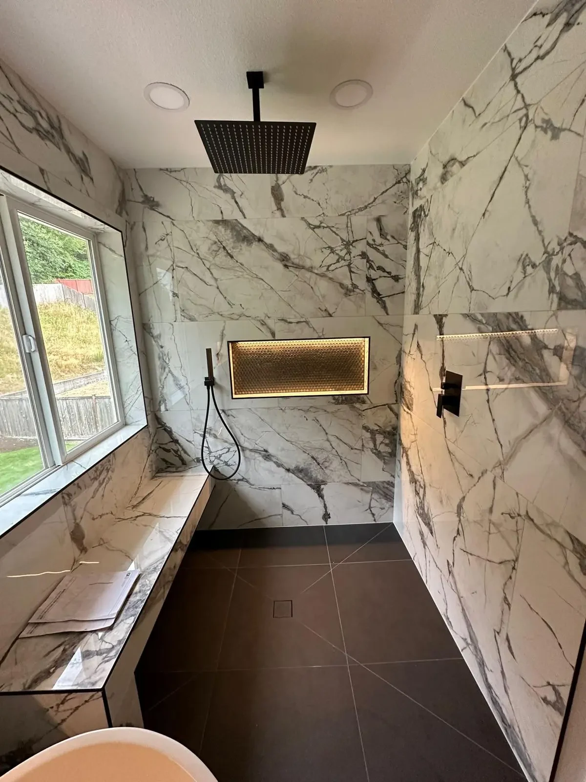 Walk-in shower with veined finishes and illuminated niche