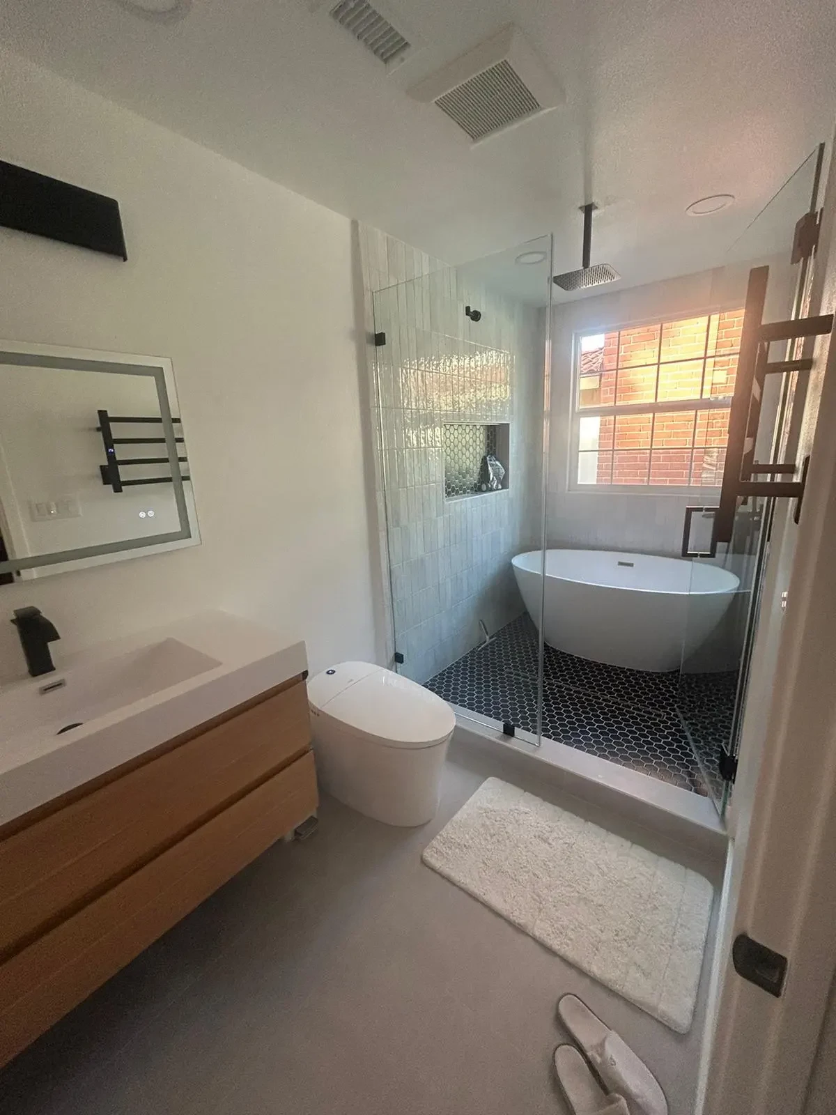 Bathroom with wood-tone vanity, glass shower and freestanding bath